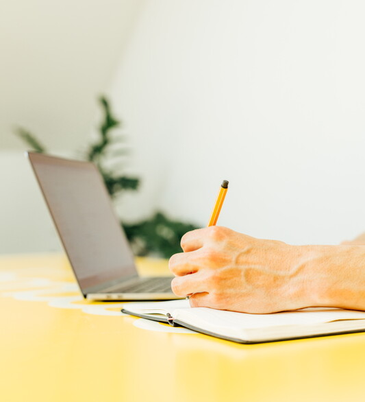 laptop op geel bureau met hand